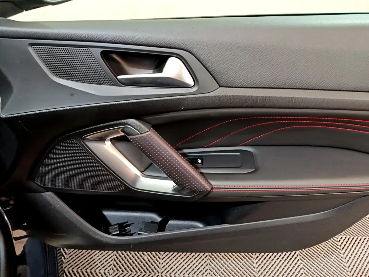 Détail de la porte côté gauche de la Peugeot 308 GT Line 2016, avec surpiqûres rouges et poignée en cuir noir perforé.