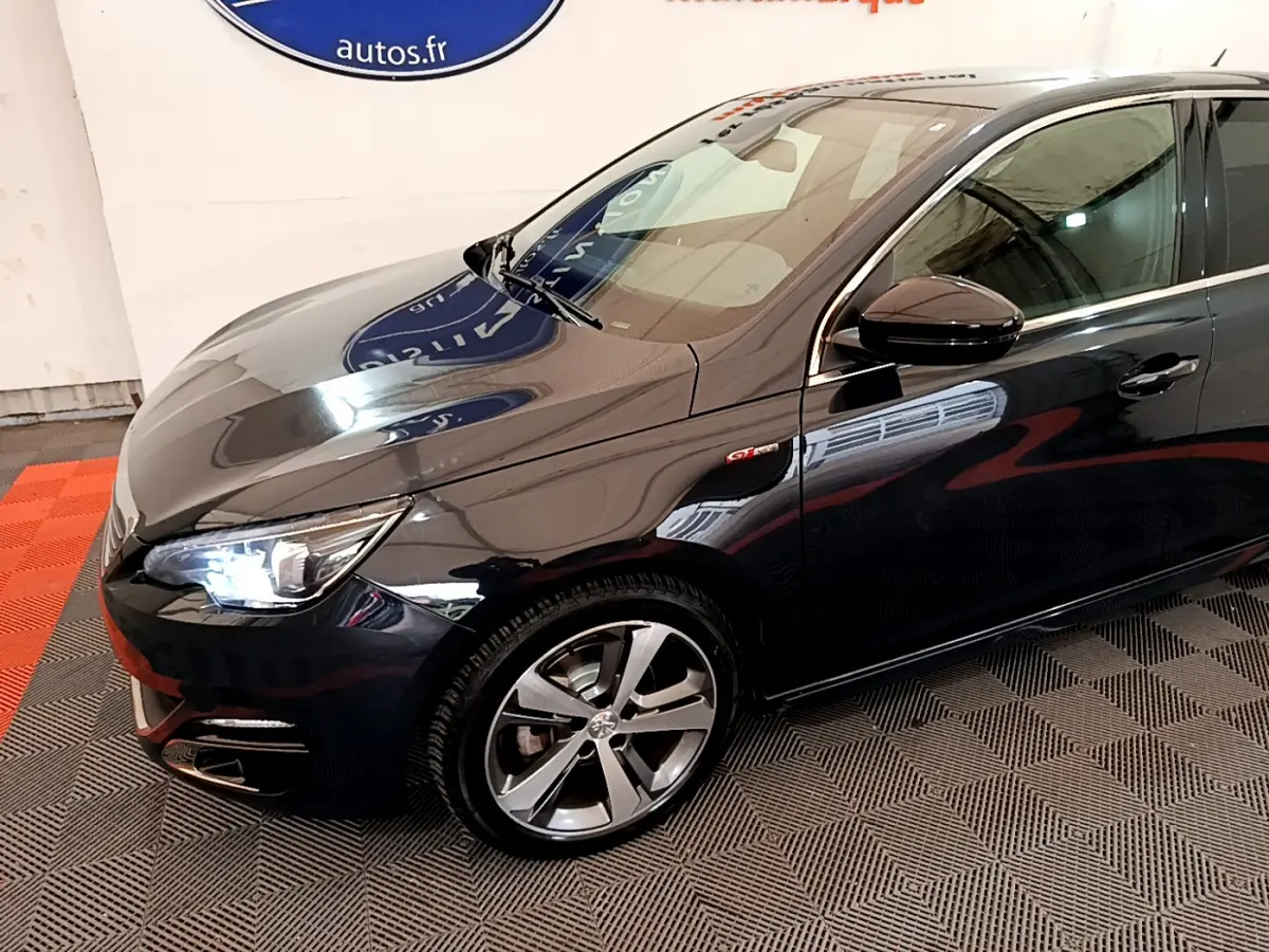 Vue 3/4 avant droit d'une Peugeot 308 gris foncé avec phares LED et jantes alliage distinctives.