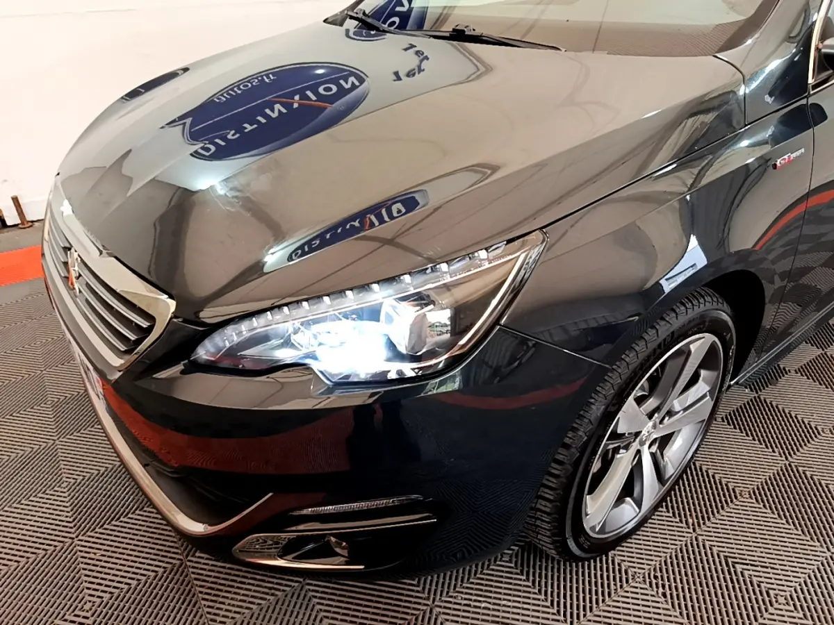 Vue 3/4 avant droit d'une Peugeot 308 gris foncé avec phares LED allumés et jantes alliage distinctives.