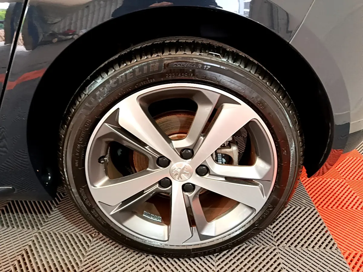 Gros plan sur la roue avant gauche du Peugeot 308 gris foncé, mettant en valeur la jante alliage et le pneu Michelin.