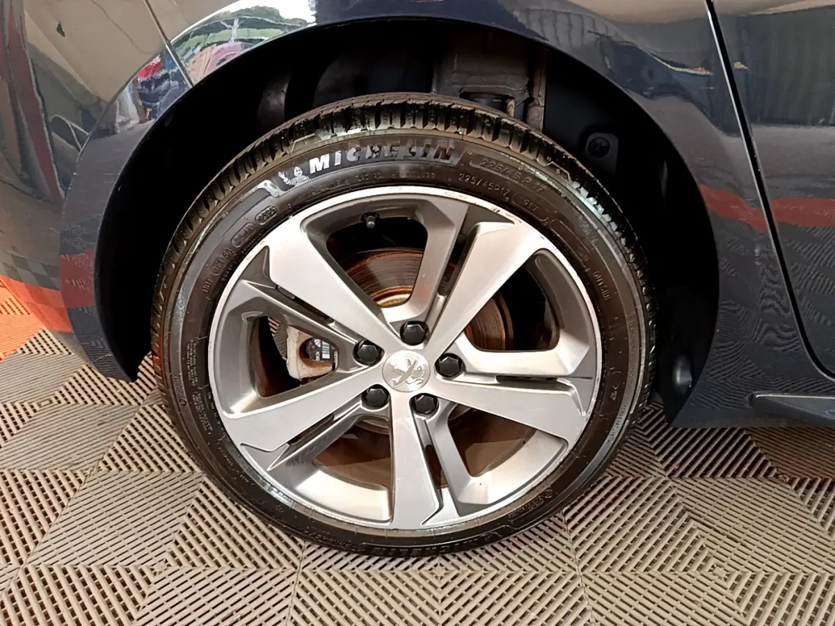 Gros plan sur la roue avant gauche gris foncé d'une Peugeot 308 1.2 PureTech 130 S&S GT Line de 2016 avec jante alliage.