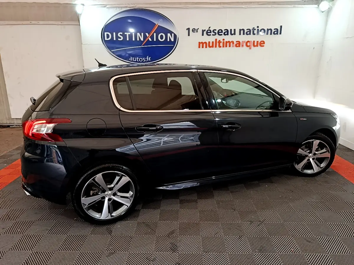 Peugeot 308 gris foncé vue de profil côté gauche, avec jantes alliage et feux arrière LED en intérieur showroom.