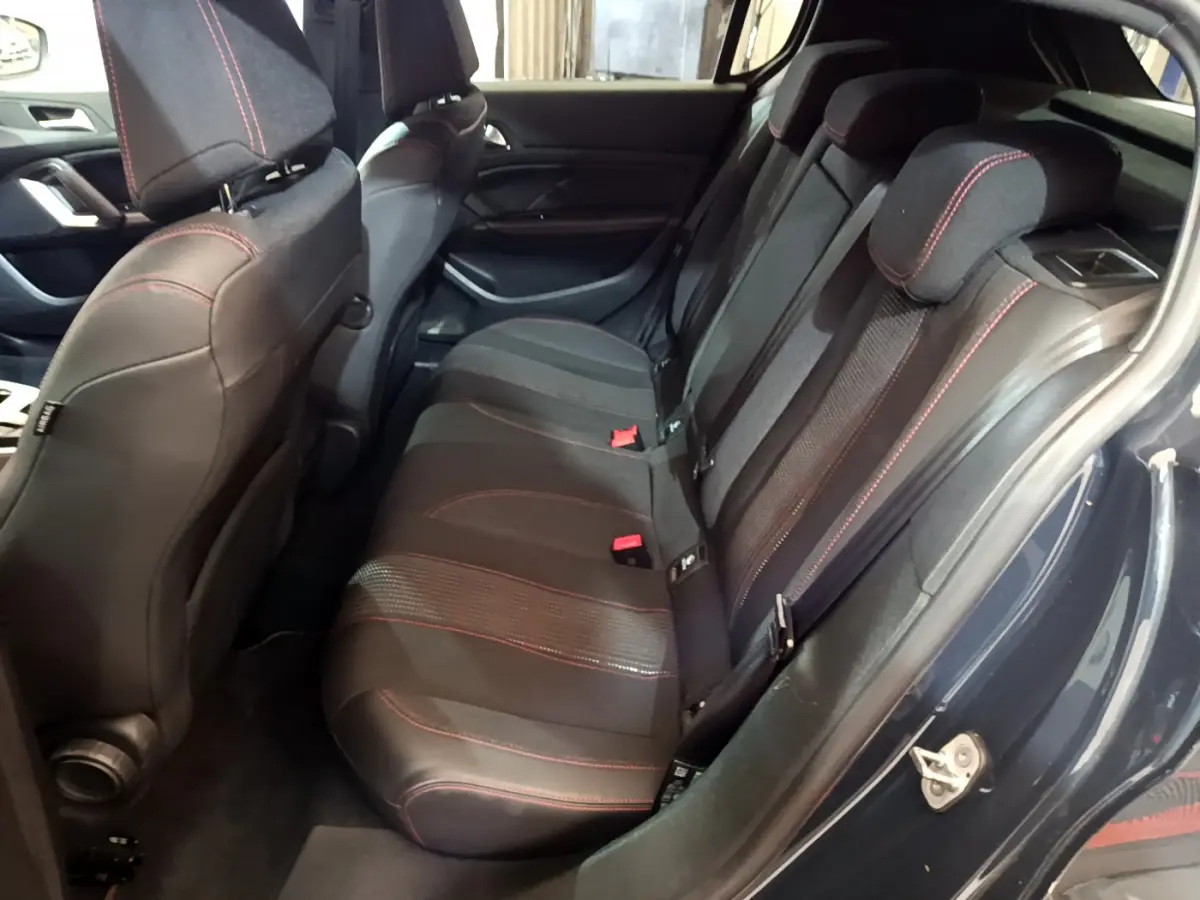 Vue latérale droite de l'habitacle arrière d'une Peugeot 308 gris foncé, sièges tissu noir avec surpiqûres rouges.