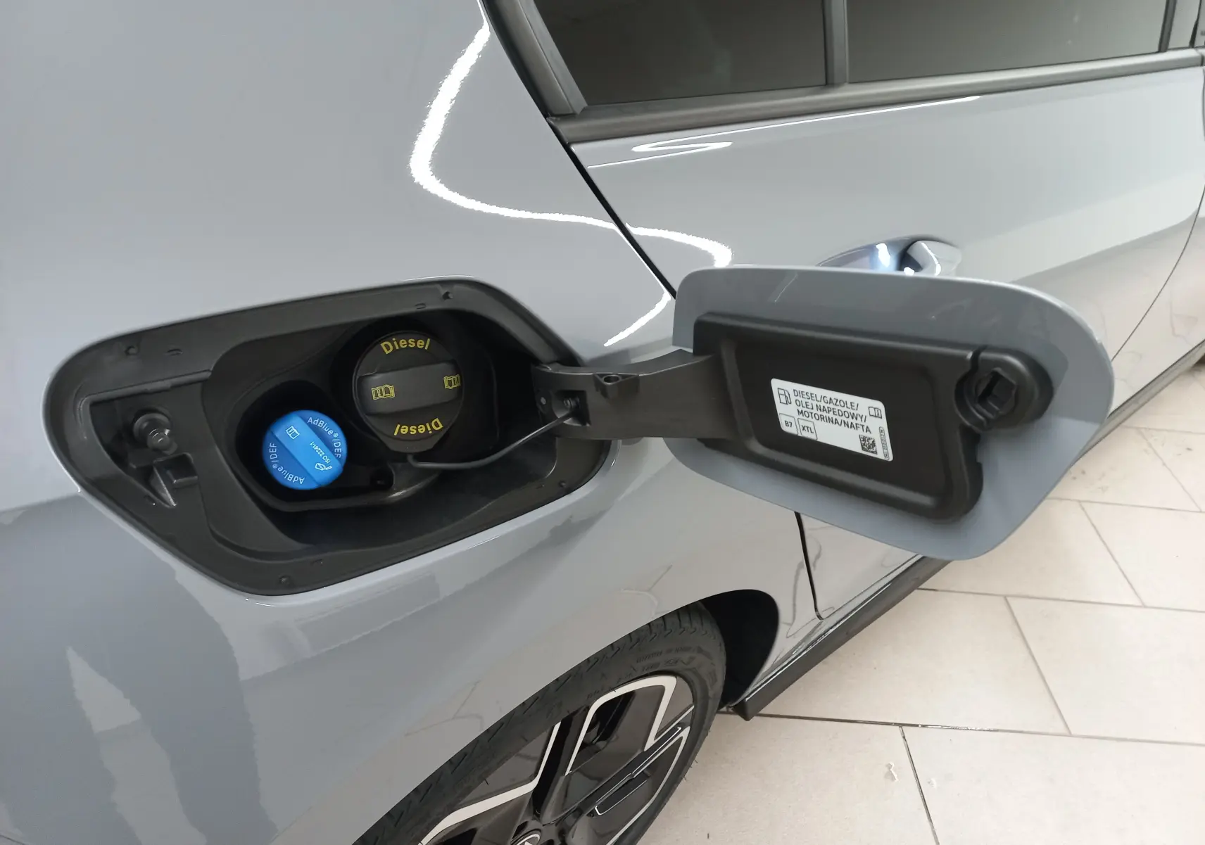 Vue rapprochée de la trappe à carburant côté gauche d'une Volkswagen Golf gris lunaire avec bouchons Diesel et AdBlue visibles.