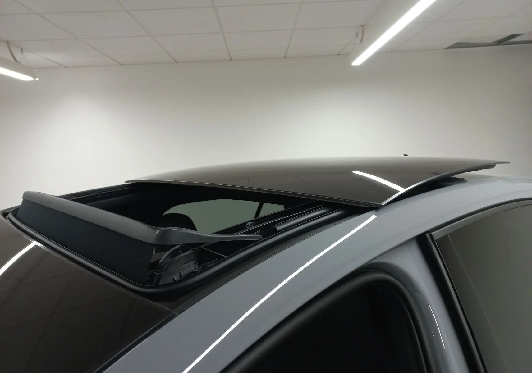 Toit ouvrant panoramique ouvert vu en gros plan sur une Volkswagen Golf gris lunaire côté droit.