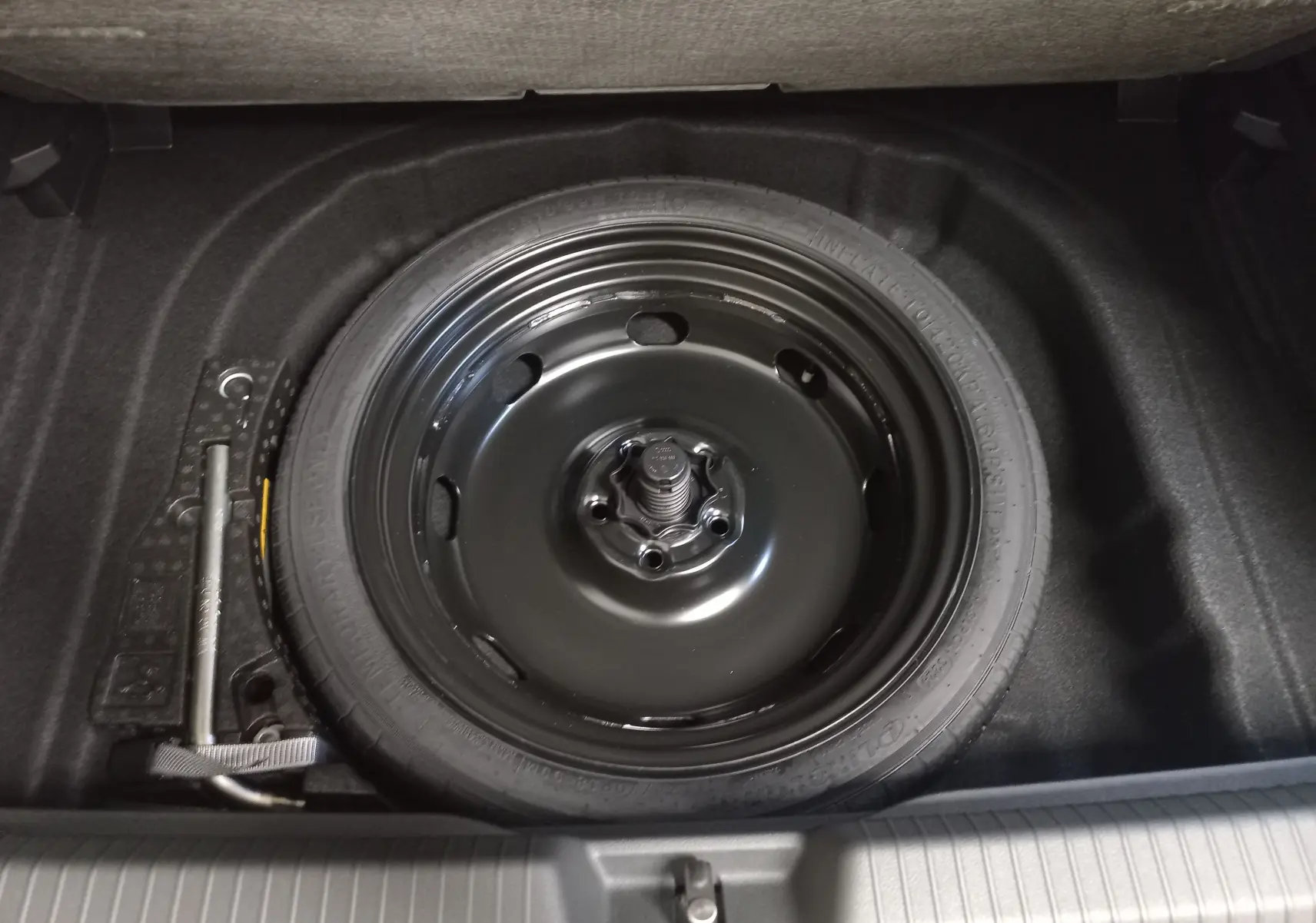 Gros plan sur la roue de secours à encombrement réduit dans le coffre d’une Volkswagen Golf gris lunaire 2026.