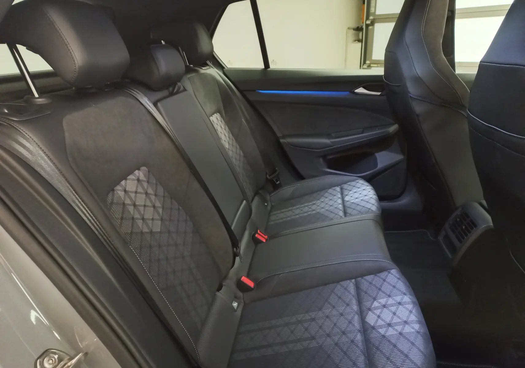 Vue latérale intérieure des sièges arrière de la Volkswagen Golf 2.0 TDI R-Line gris lunaire avec sellerie tissu et cuir noir.