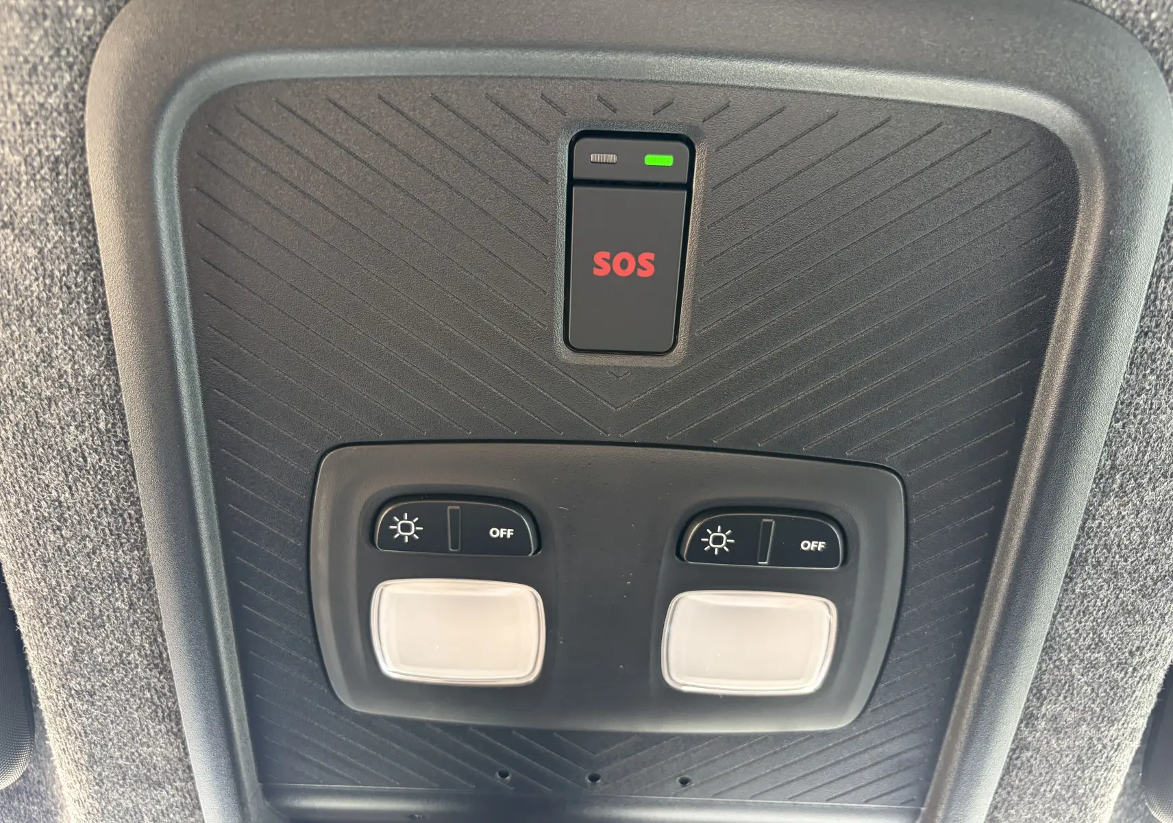Vue rapprochée du plafonnier intérieur du Dacia Duster III kaki, avec bouton SOS et commandes d'éclairage.