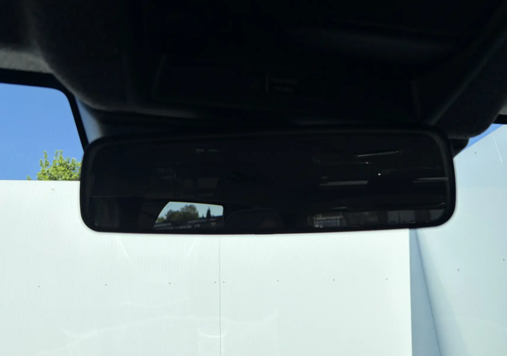 Rétroviseur intérieur du Dacia Duster III hybride 2026, vue frontale avec reflet partiel de l'extérieur.