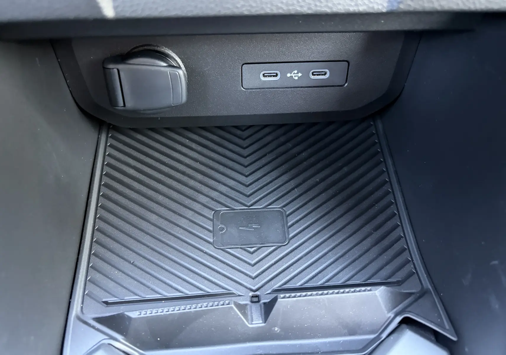 Gros plan sur la console centrale noire du Dacia Duster III 2026, montrant les prises USB type C et le chargeur à induction.