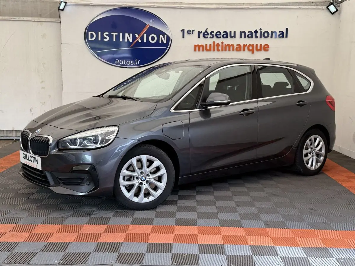 BMW Série 2 Active Tourer gris foncé vue 3/4 avant côté gauche dans un showroom multimarque.