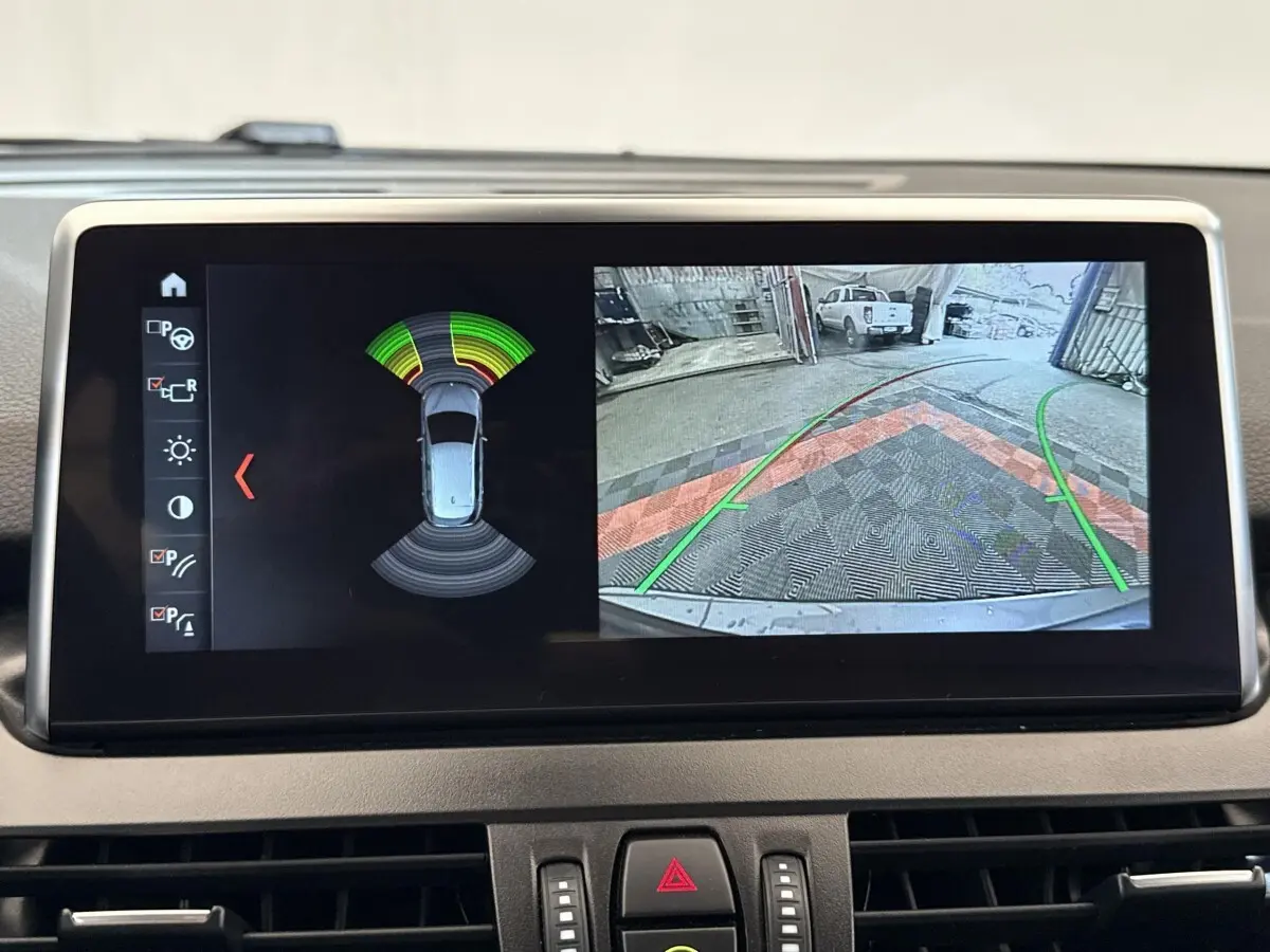 Écran tactile intérieur montrant l’aide au stationnement et la caméra de recul de la BMW Série 2 Active Tourer gris foncé.