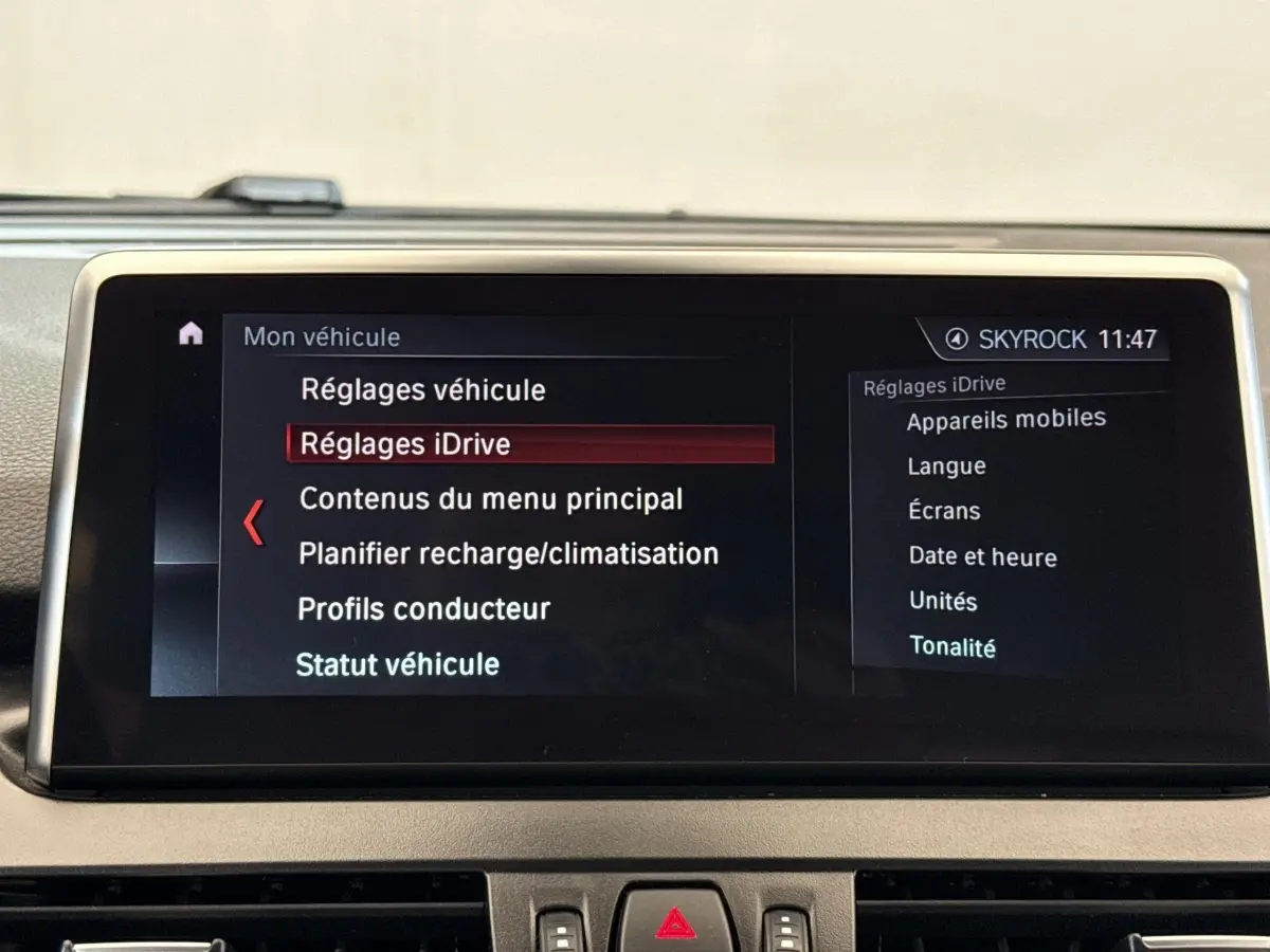 Écran tactile central affichant le menu iDrive de la BMW Série 2 Active Tourer 225xe gris foncé, vue intérieure frontale.