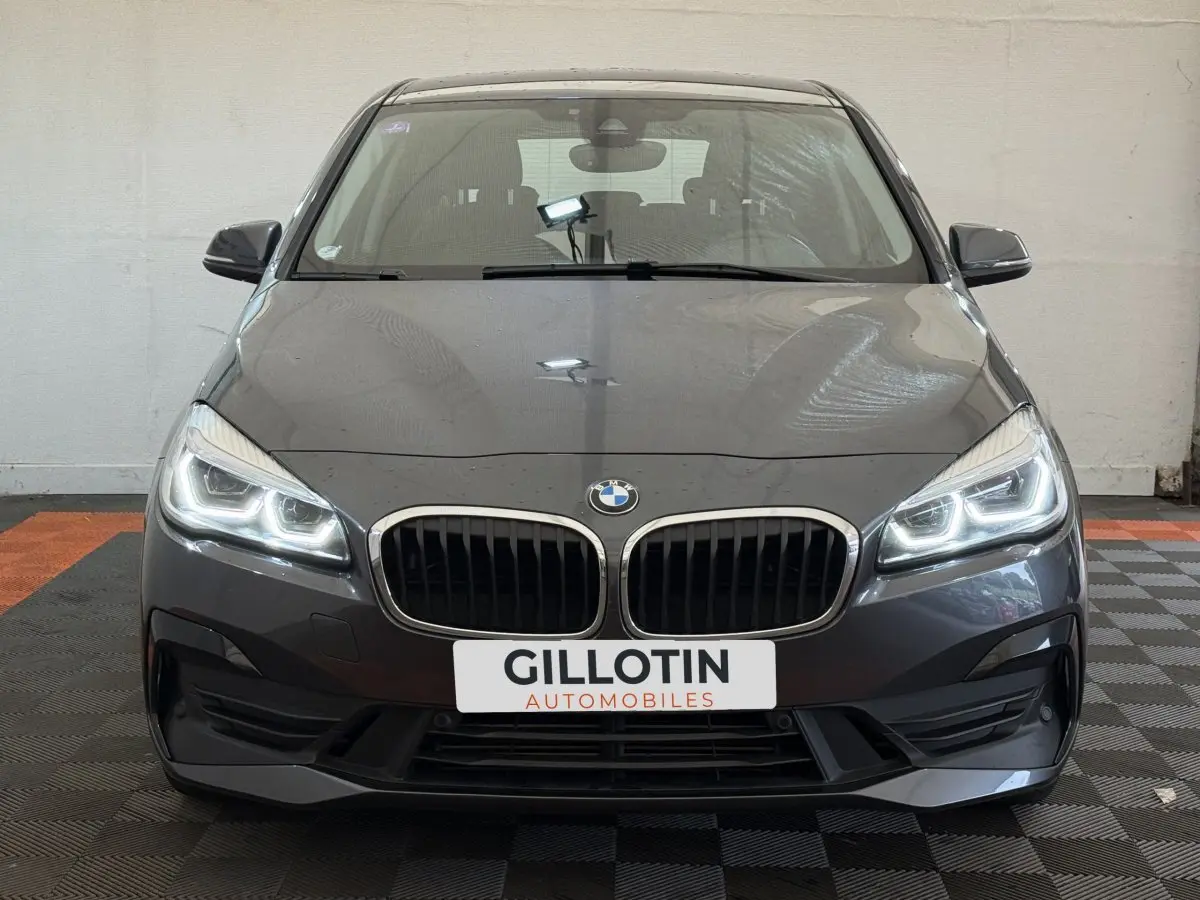 Vue frontale d'une BMW Série 2 Active Tourer gris foncé avec phares LED allumés et calandre double haricot.