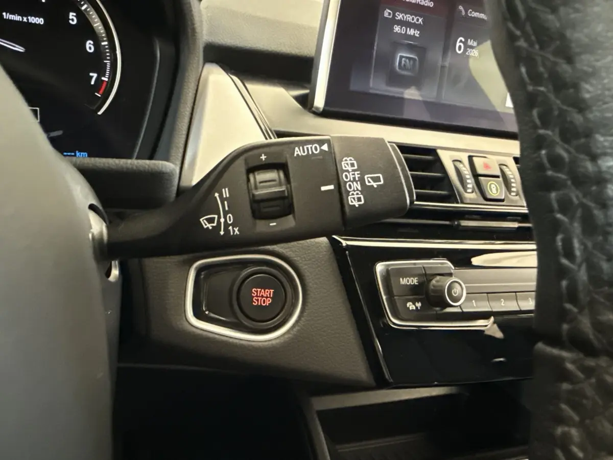 Détail intérieur côté gauche du tableau de bord gris foncé avec bouton Start/Stop et commandes essuie-glaces BMW Série 2 Active Tourer.
