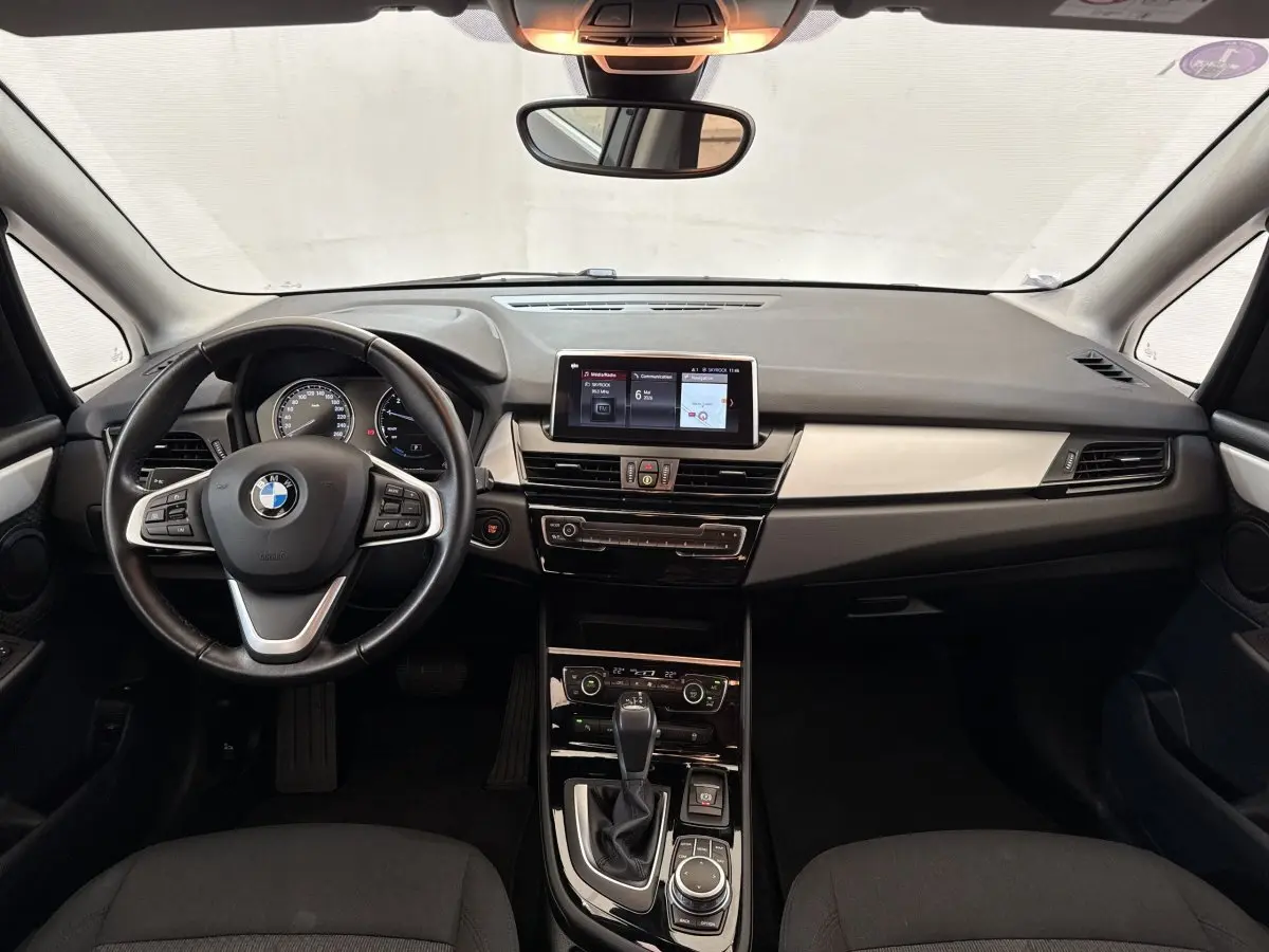 Vue frontale de l'intérieur gris foncé du BMW Série 2 Active Tourer 225xe avec tableau de bord et écran tactile central.