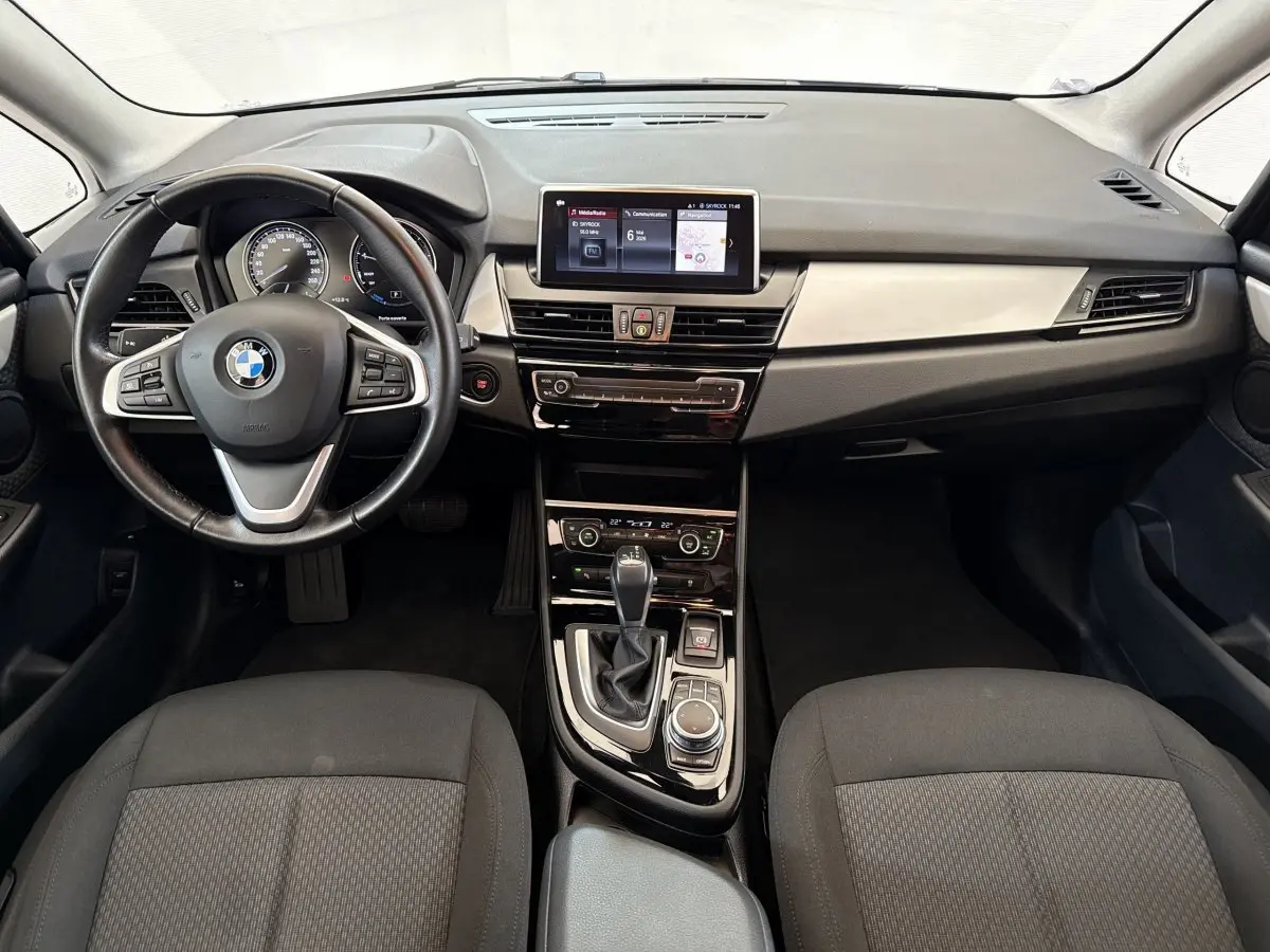 Vue intérieure avant de la BMW Série 2 Active Tourer 225xe, tableau de bord noir avec écran tactile central et volant cuir.