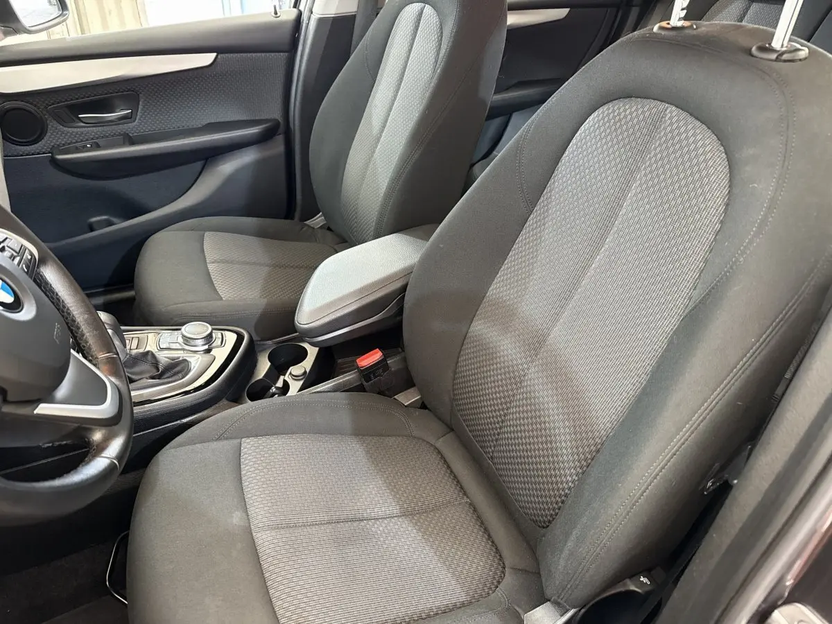 Vue intérieure côté conducteur de la BMW Série 2 Active Tourer 225xe gris foncé, montrant les sièges tissu et la console centrale.