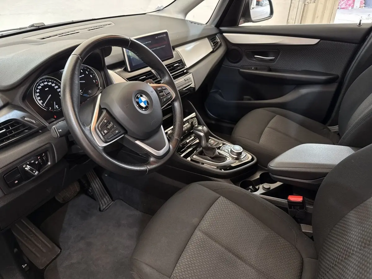 Vue intérieure côté conducteur de la BMW Série 2 Active Tourer 225xe gris foncé, avec volant cuir multifonctions et écran tactile central.