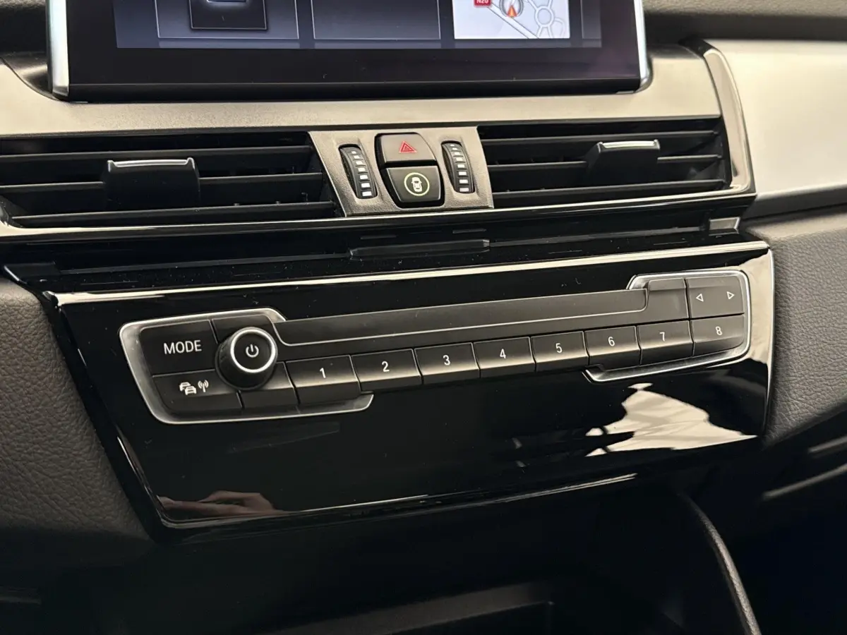 Détail du tableau de bord noir brillant de la BMW Série 2 Active Tourer 225xe avec commandes multimédia et ventilation.