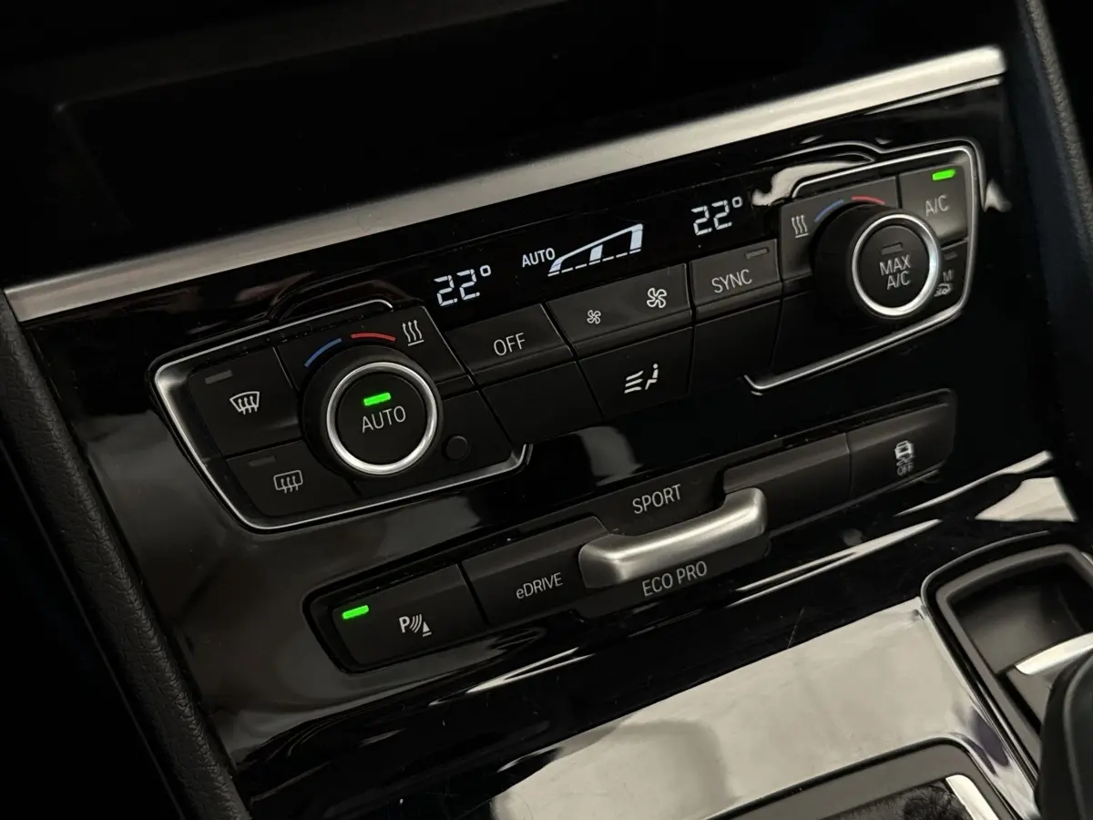 Détail du panneau de commande de la climatisation bi-zone et modes de conduite sur BMW Série 2 Active Tourer gris foncé.