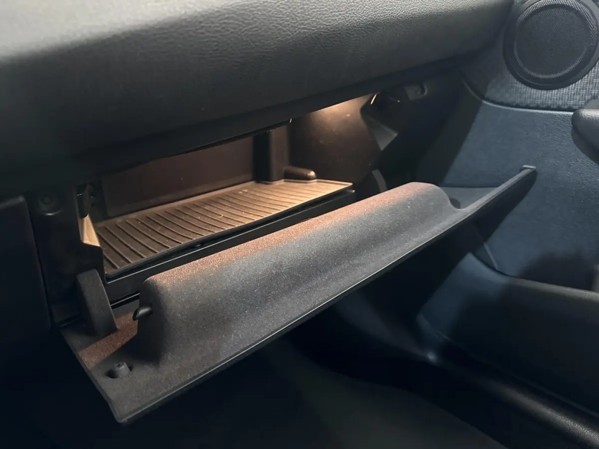 Gros plan sur la boîte à gants ouverte côté passager de la BMW Série 2 Active Tourer 225xe gris foncé, intérieur sombre.