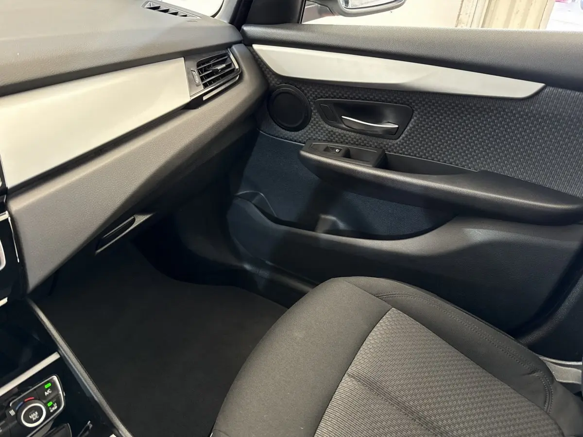 Vue intérieure côté passager avant de la BMW Série 2 Active Tourer 225xe, avec sellerie noire et panneau de porte texturé.