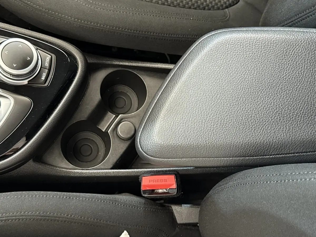 Gros plan intérieur sur la console centrale noire et les porte-gobelets de la BMW Série 2 Active Tourer 225xe gris foncé.