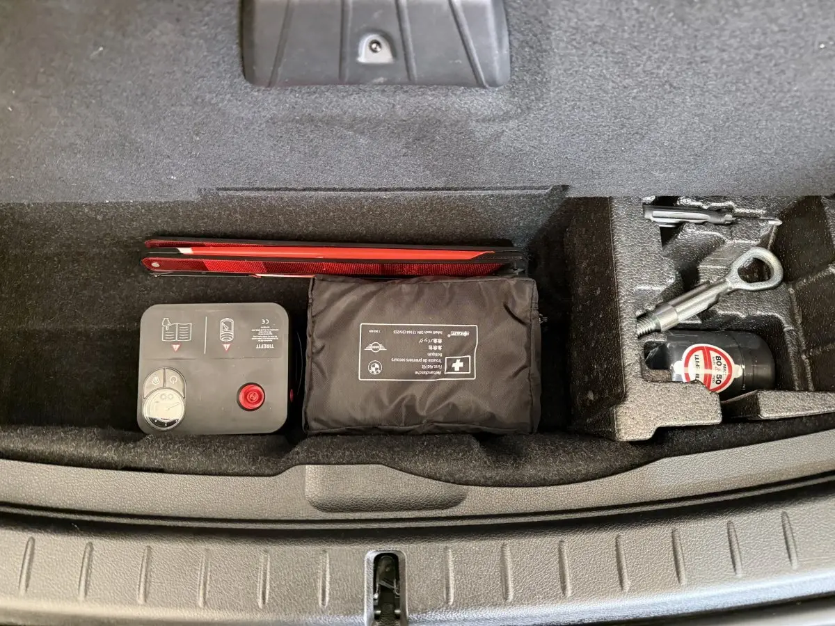 Vue plongeante sur le compartiment de rangement sous coffre d'une BMW Série 2 Active Tourer gris foncé avec kit de secours et outils.