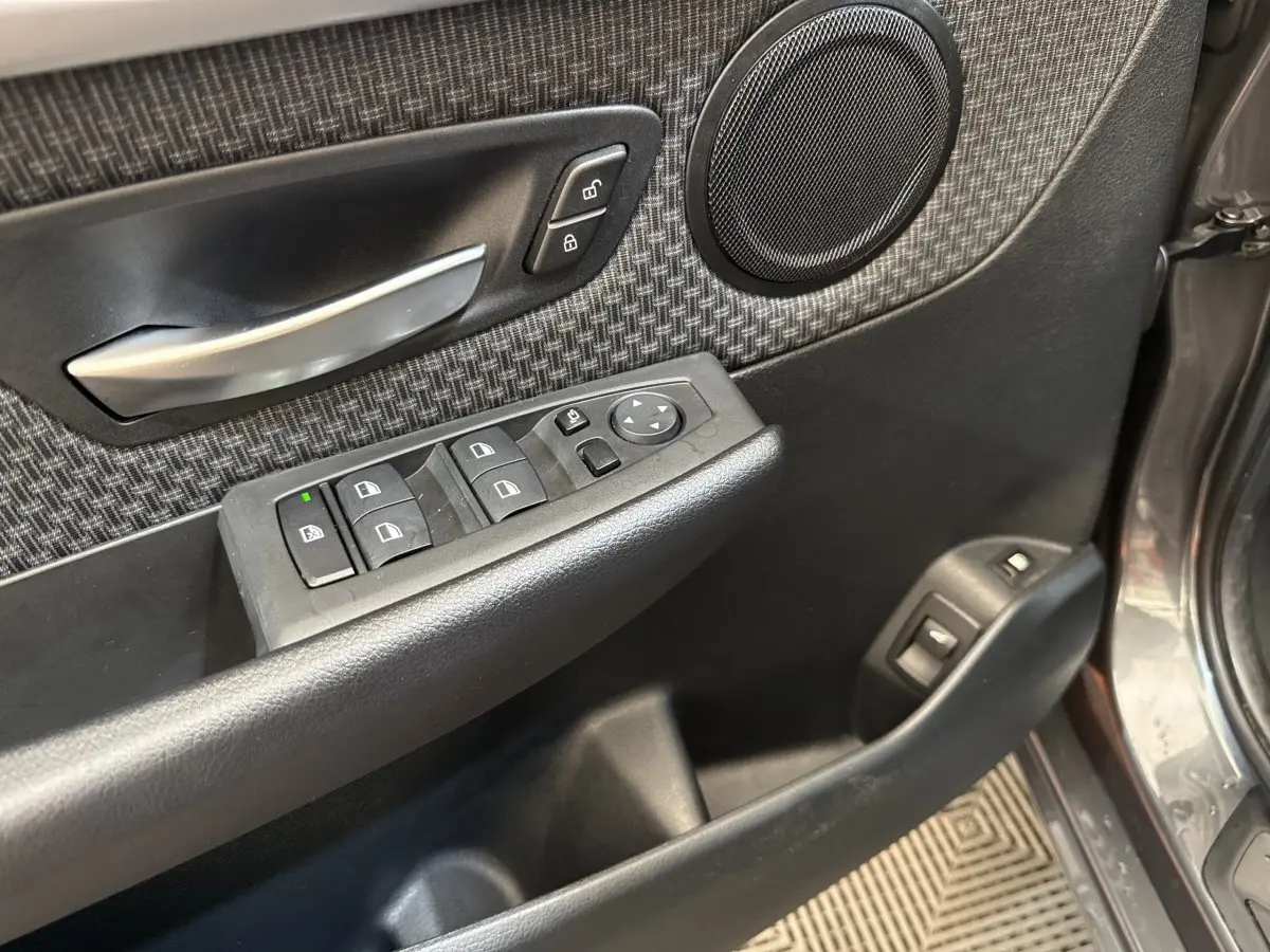 Détail de la porte avant gauche gris foncé d’une BMW Série 2 Active Tourer avec commandes électriques et haut-parleur intégré.