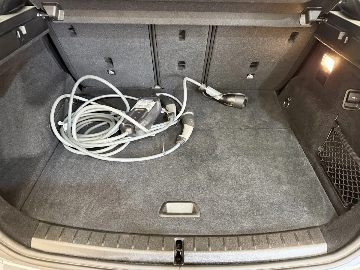 Coffre ouvert vu de face d’une BMW Série 2 Active Tourer gris foncé avec câble de recharge hybride posé au sol.