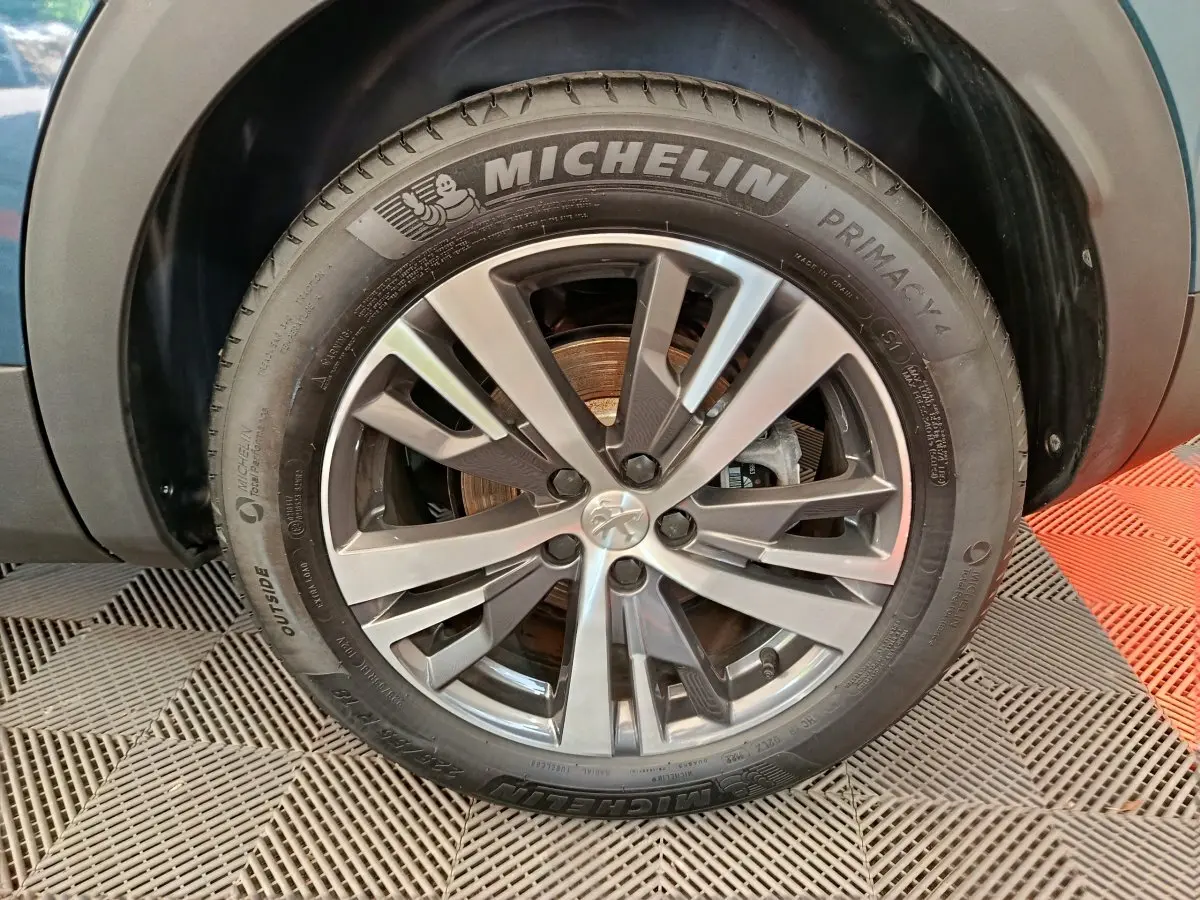 Gros plan sur la jante alliage et pneu Michelin d'un Peugeot 3008 bleu, côté droit avant.