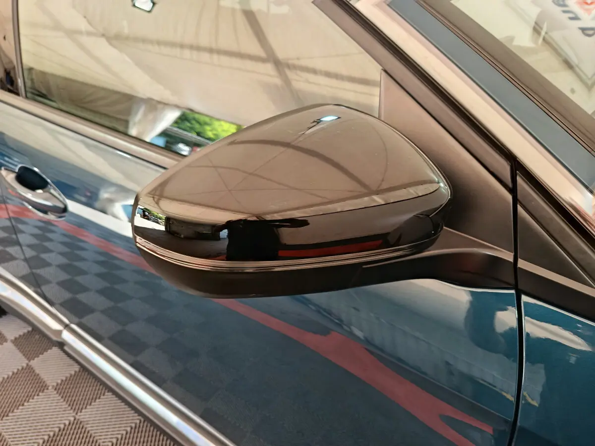 Rétroviseur côté droit noir brillant sur Peugeot 3008 bleu, vue rapprochée du profil avant du véhicule.