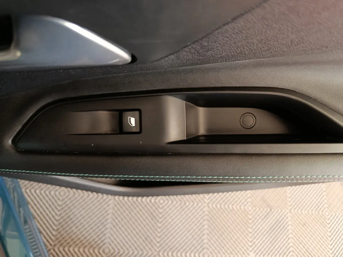 Gros plan sur la commande de lève-vitre côté gauche de la porte d'une Peugeot 3008 bleu 2022 PureTech Allure.