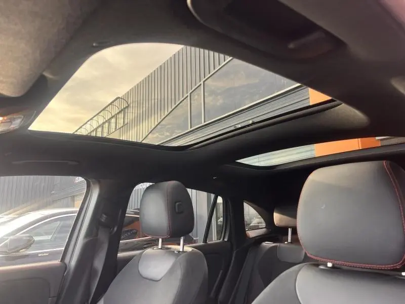 Vue intérieure du Mercedes GLA 200 d AMG Line 2021, toit ouvrant panoramique et sièges sport noirs avec surpiqûres rouges.