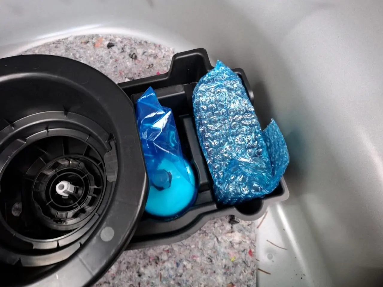 Détail du compartiment de rangement dans le coffre d’une Opel Corsa gris clair, avec kit anti-crevaison emballé.