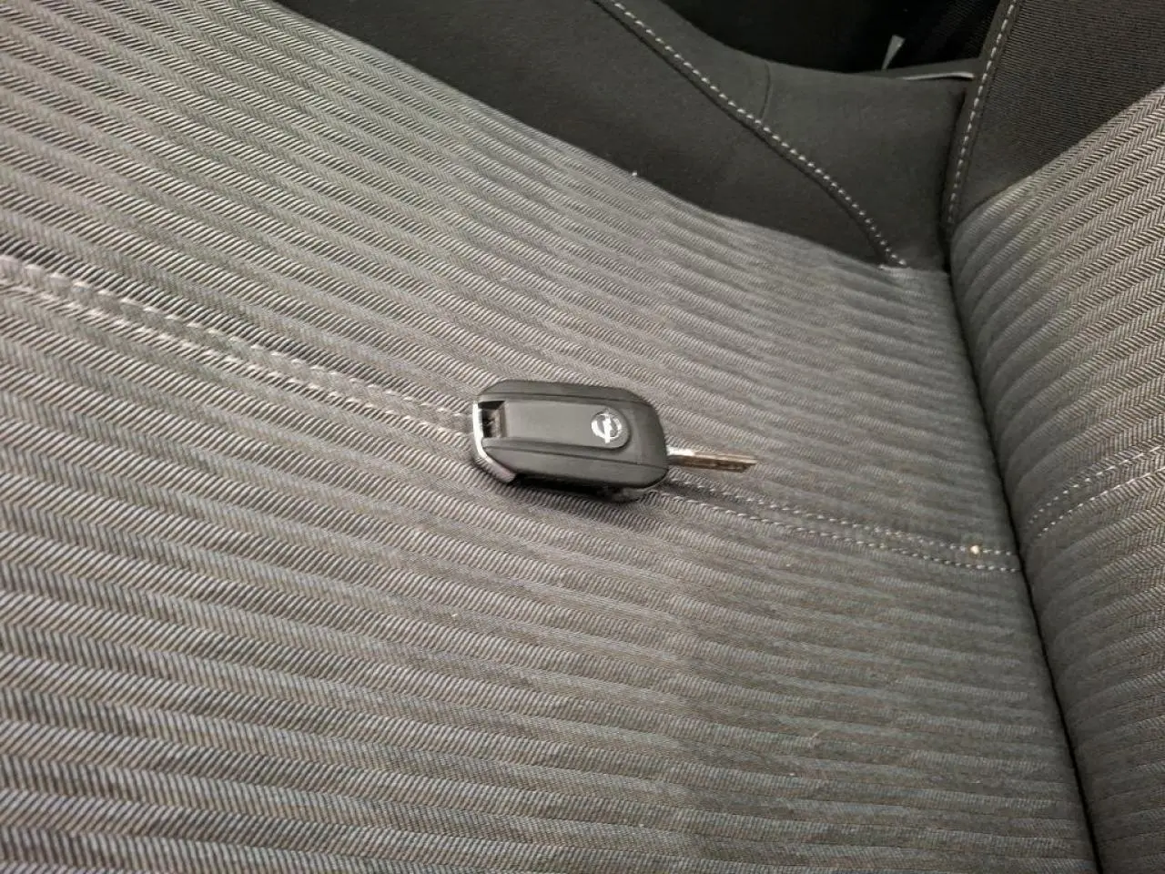 Gros plan sur la clé Opel posée sur la sellerie tissu noire de la banquette arrière de la Corsa 2023.
