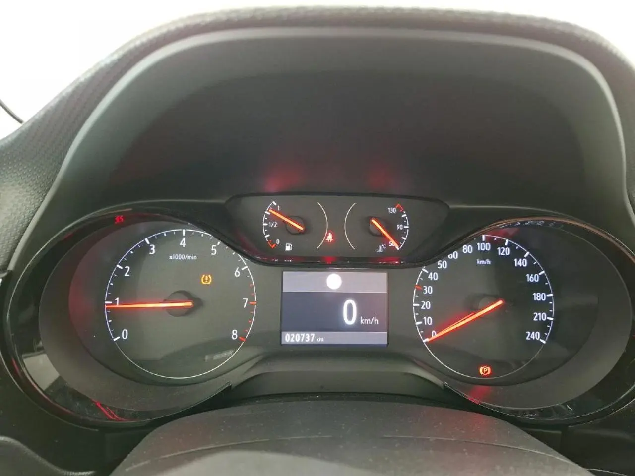 Vue rapprochée du tableau de bord digital de l'Opel Corsa gris clair, affichant 0 km/h et 20 737 km au compteur.