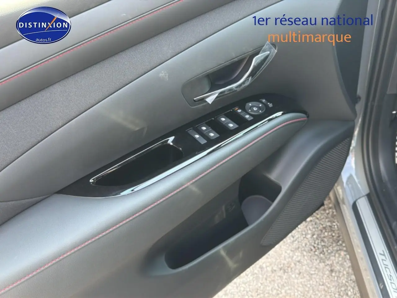 Gros plan sur la porte avant gauche gris shadow du Hyundai Tucson 2026 avec commandes de vitres et poignée intérieure.