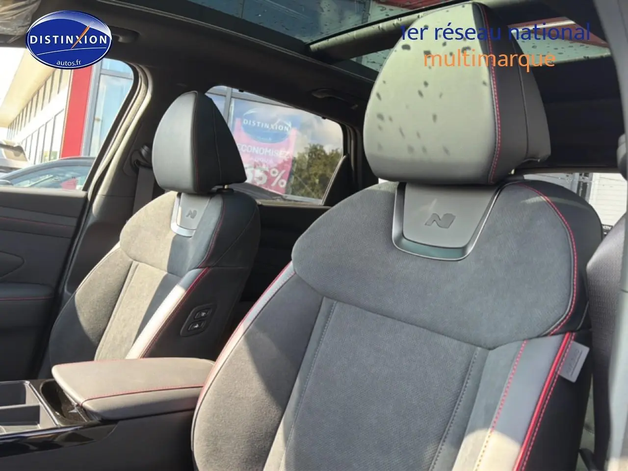 Gros plan sur les sièges avant gris alcantara avec surpiqûres rouges du Hyundai Tucson N Line 2026, intérieur lumineux.