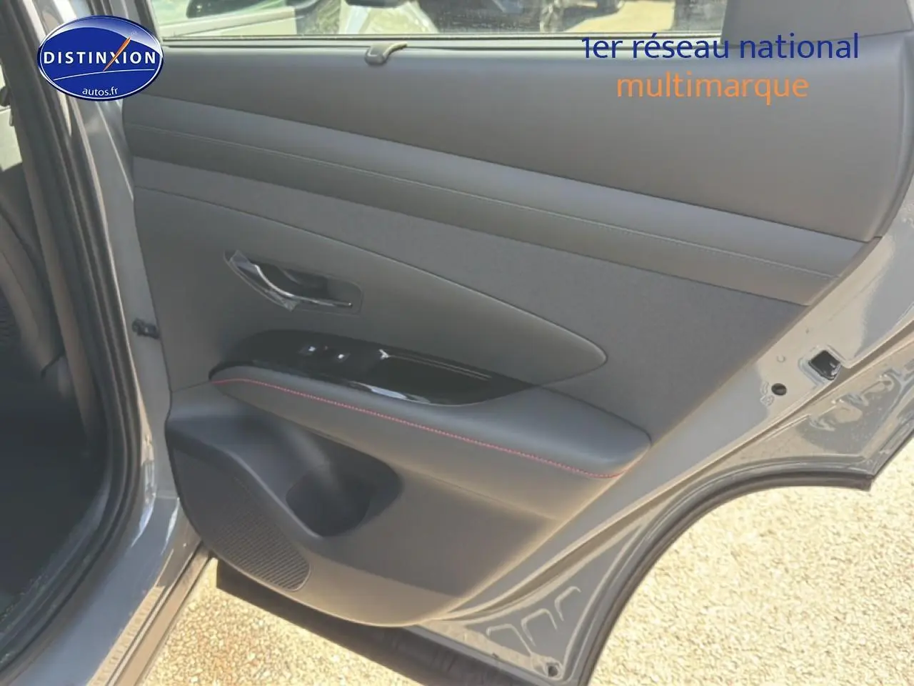Vue rapprochée de la porte arrière gauche grise shadow du Hyundai Tucson avec garniture noire et surpiqûres rouges.