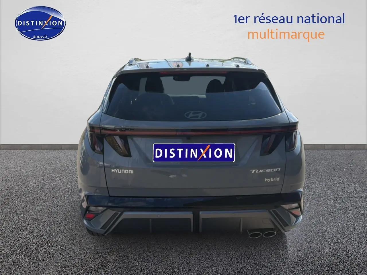Vue arrière d’un Hyundai Tucson gris shadow hybride 2026 avec feux LED et double sortie d’échappement visible à droite.