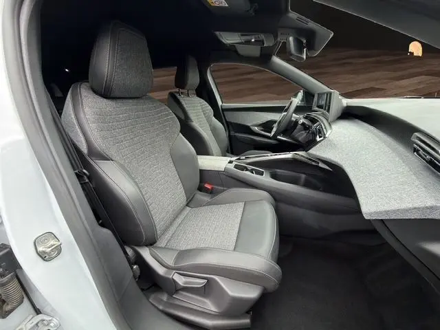 Vue intérieure côté conducteur du Peugeot 5008 Allure Hybrid blanc Okenite, sièges tissu et cuir gris avec planche de bord texturée.