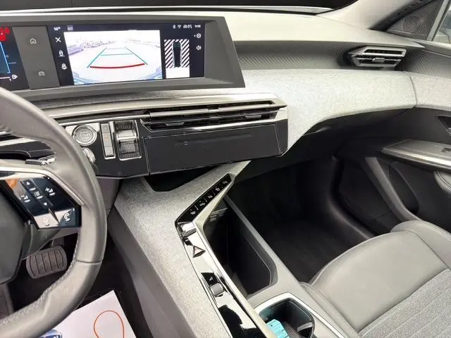 Vue intérieure de la planche de bord et console centrale du Peugeot 5008 Allure Hybrid blanc, avec écran tactile et volant partiel visible.