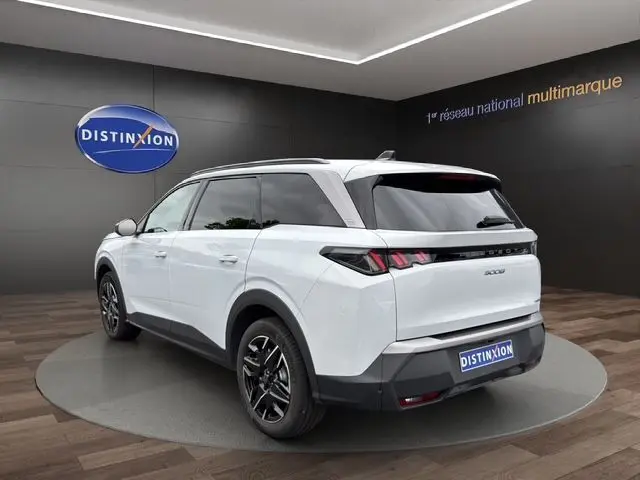 Vue 3/4 arrière droite d’un Peugeot 5008 Nouveau blanc Okenite avec jantes alliage 18'' et bandeau noir laqué entre feux arrière.