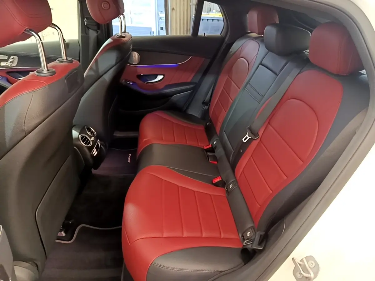 Vue intérieure arrière côté droit du Mercedes GLC 300 e AMG Line blanc, sièges en cuir bicolore rouge et noir.
