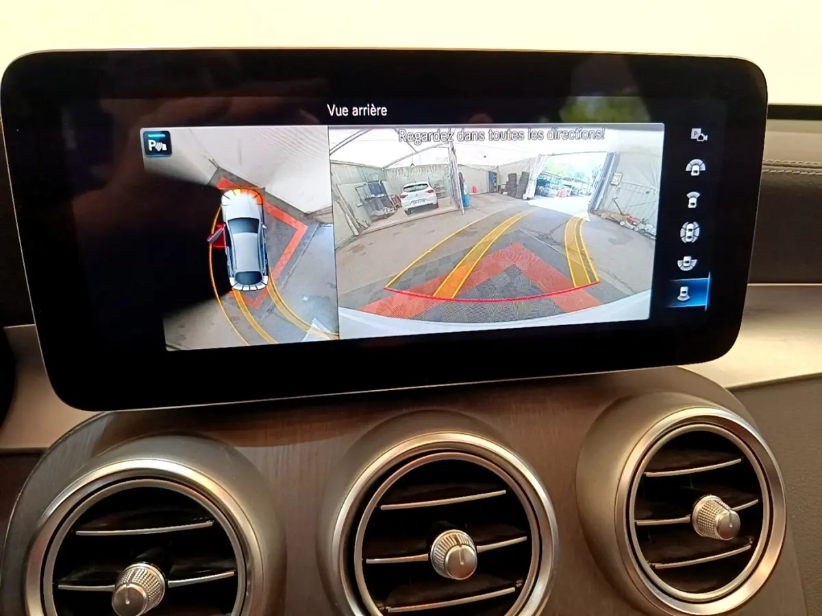 Écran central affichant la caméra de recul et vue 360° d’un Mercedes GLC Coupé blanc en intérieur.