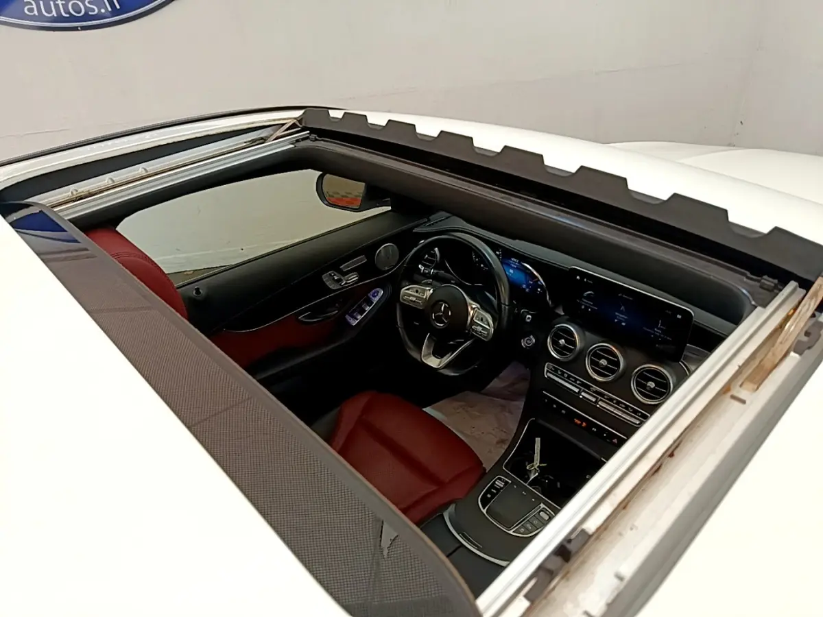 Vue plongeante sur l’intérieur rouge et noir d’un Mercedes GLC Coupé blanc, avec toit ouvrant panoramique ouvert.