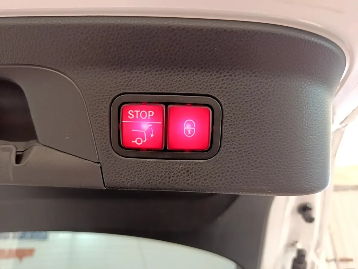 Gros plan sur les boutons rouges d'ouverture et de verrouillage électrique du coffre d'un Mercedes GLC Coupé blanc.