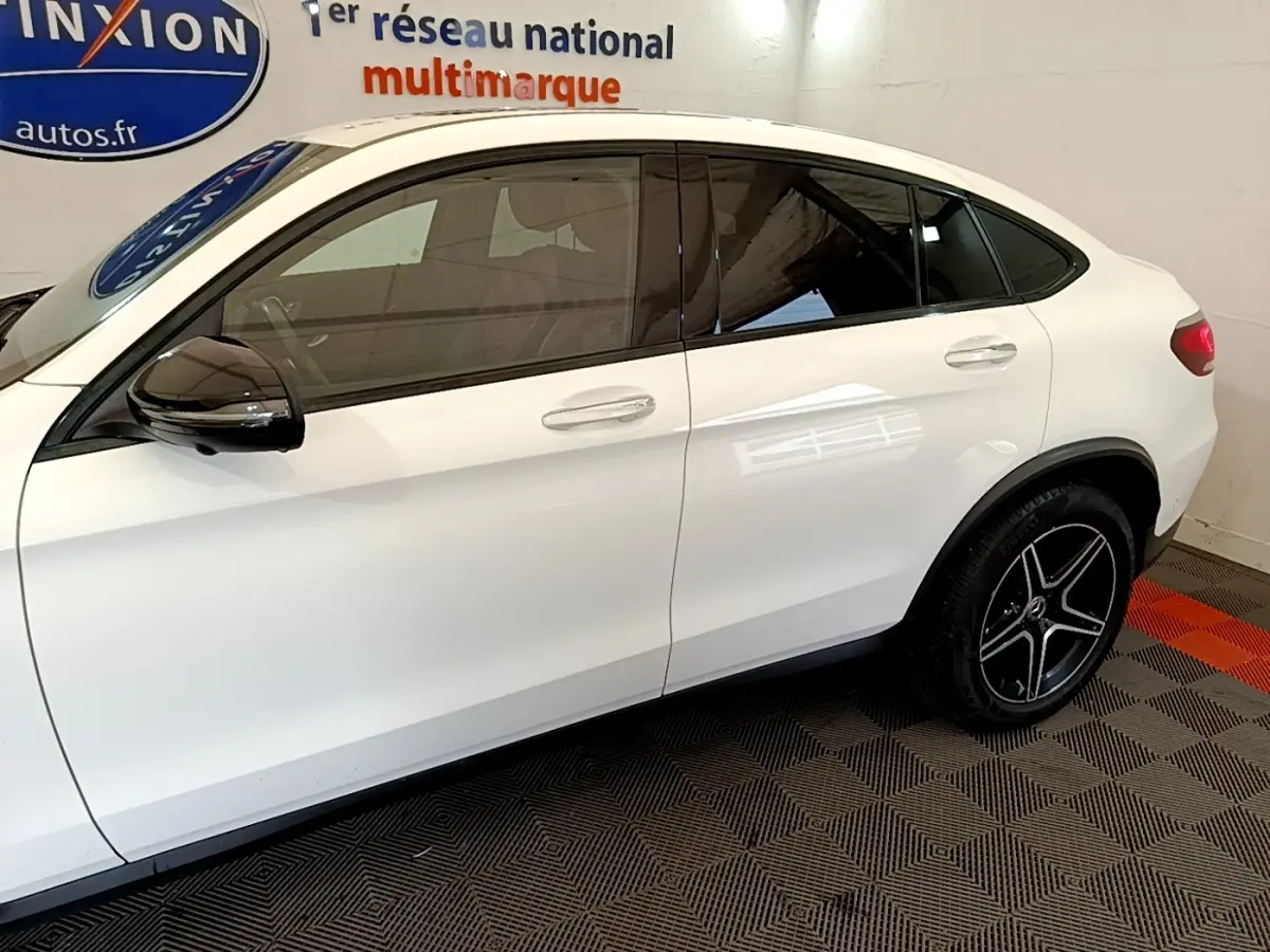 Vue latérale droite d’un Mercedes GLC Coupé blanc avec jantes noires et rétroviseurs noirs brillants.